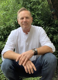 a man sitting on a bench in front of bushes